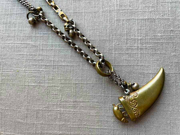 closeup of antique bronze tooth match safe with pig pendant on chain mix