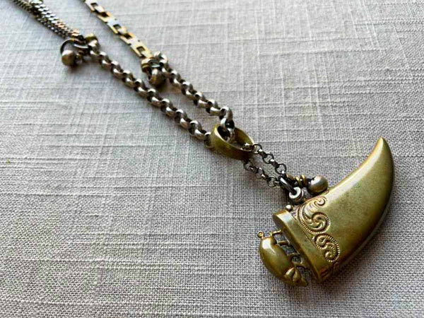 closeup of antique bronze tooth match safe with pig pendant on chain mix