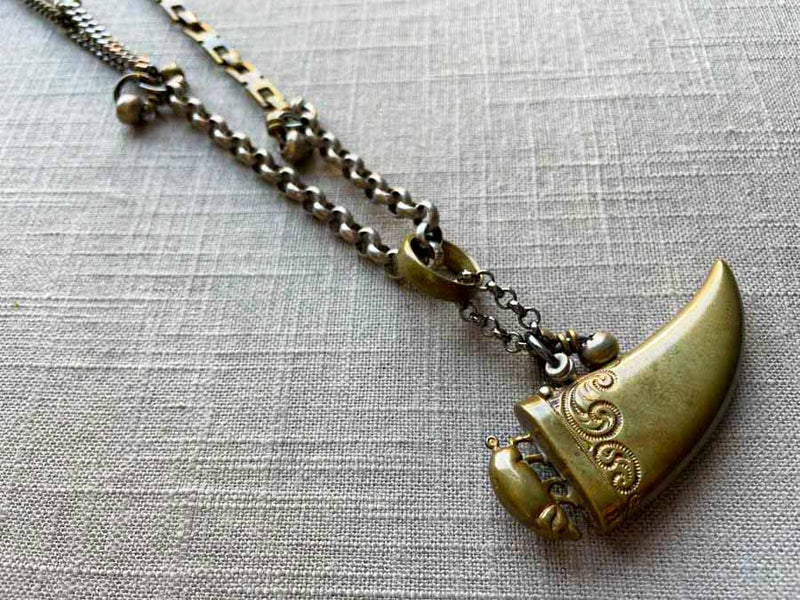 closeup of antique bronze tooth match safe with pig pendant on chain mix