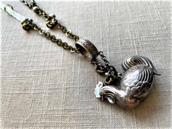 closeup of antique sterling silver rooster pendant on chain mix