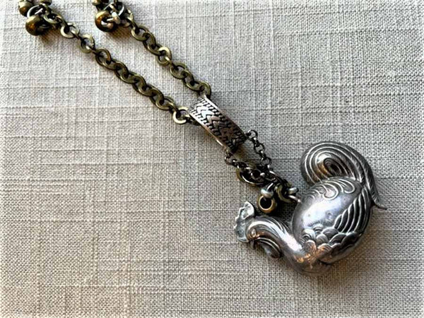 closeup of antique sterling silver rooster pendant on chain mix 