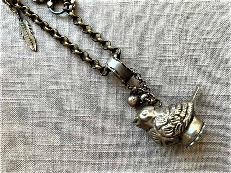 closeup of antique tin salt shaker (bird) pendant on chain mix