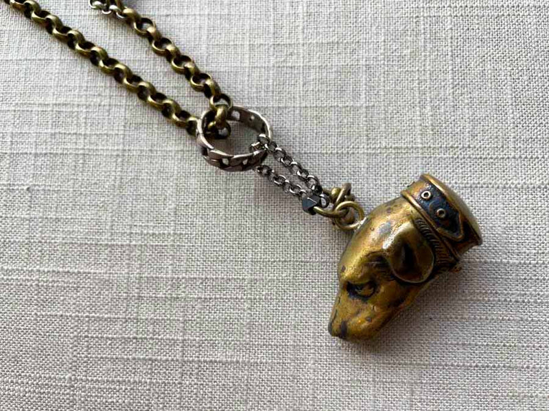 closeup of antique bronze dog match safe pendant on chain mix