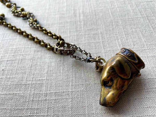 closeup of antique bronze dog match safe pendant on chain mix