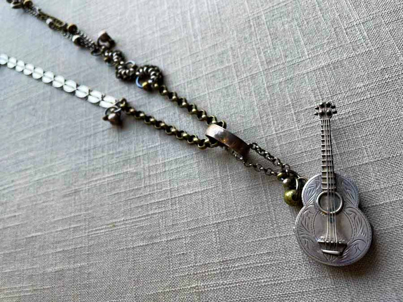 top view of antique sterling silver guitar pendant on chain mix