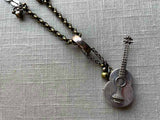 closeup of antique sterling silver guitar pendant on chain mix