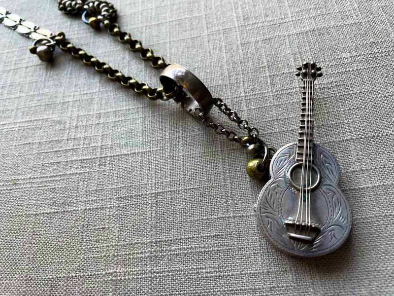 closeup of antique sterling silver guitar pendant on chain mix