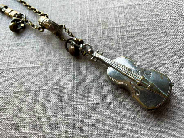 closeup of antique sterling silver cello pendant on chain mix