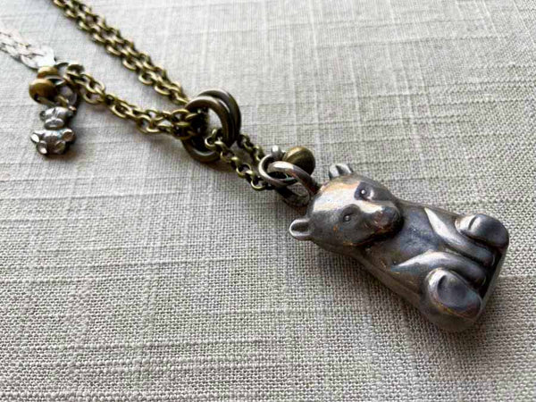 closeup of antique sterling silver bear rattle pendant on chain mix