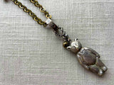 closeup of antique sterling silver bear rattle pendant on chain mix