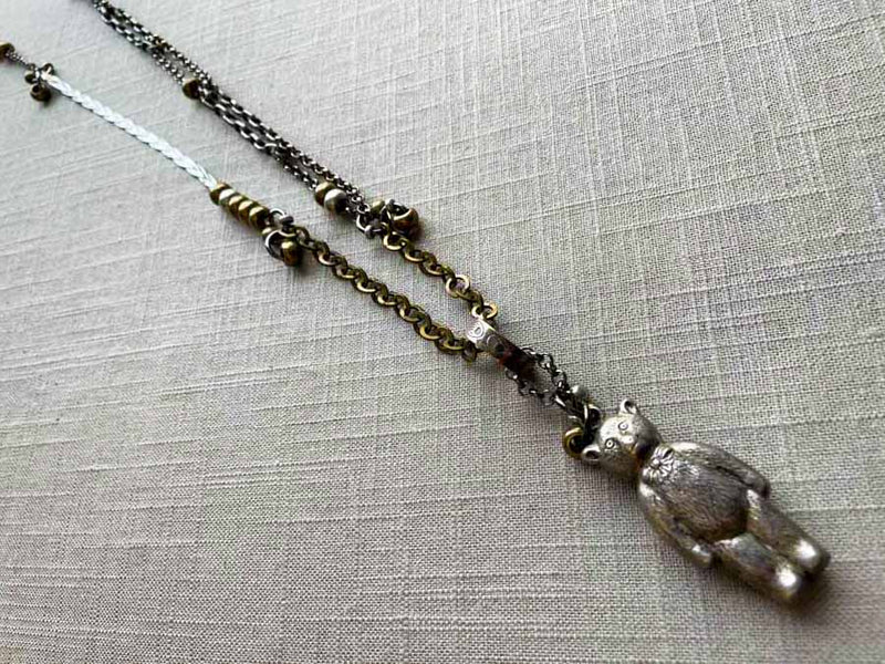 top view of antique sterling silver bear rattle pendant on chain mix