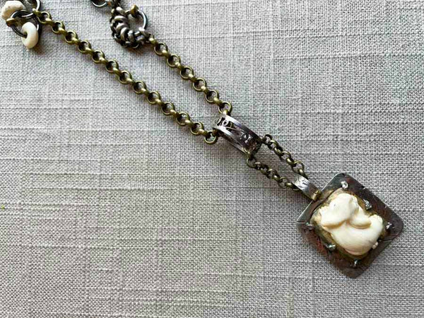 closeup of antique carved fossilized ivory rabbit pendant on chain mix