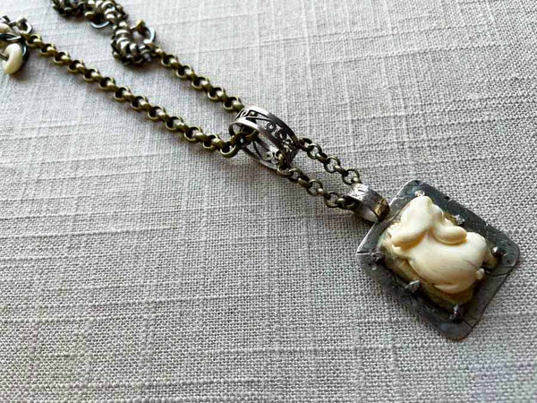 closeup of antique carved fossilized ivory rabbit pendant on chain mix