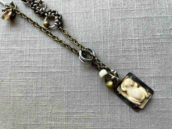 closeup of antique carved fossilized ivory frog pendant on chain mix