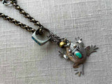 closeup of antique sterling silver frog pendant on chain mix