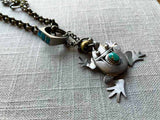 closeup of antique sterling silver frog pendant on chain mix