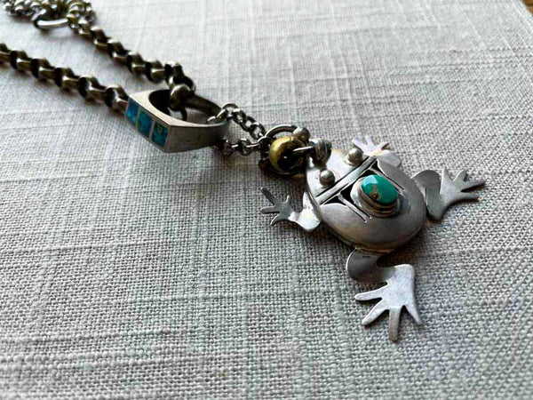 closeup of antique sterling silver frog pendant on chain mix