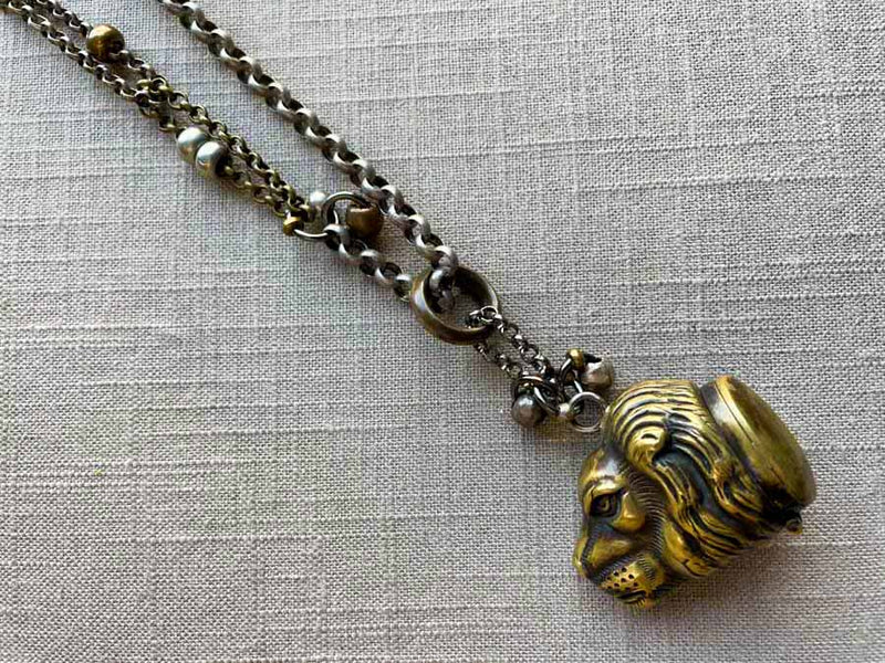 closeup of antique bronze match safe (lion) pendant on chain mix