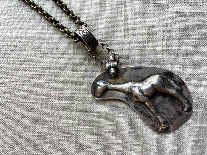 closeup of antique sterling silver giraffe candy mold pendant on chain mix