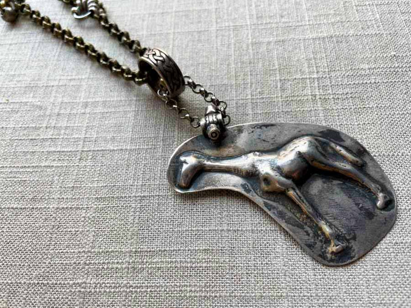 closeup of antique sterling silver giraffe candy mold pendant on chain mix