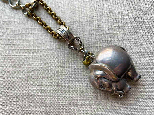 closeup of antique sterling silver elephant rattle pendant on chain mix