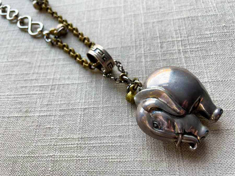 closeup of antique sterling silver elephant rattle pendant on chain mix