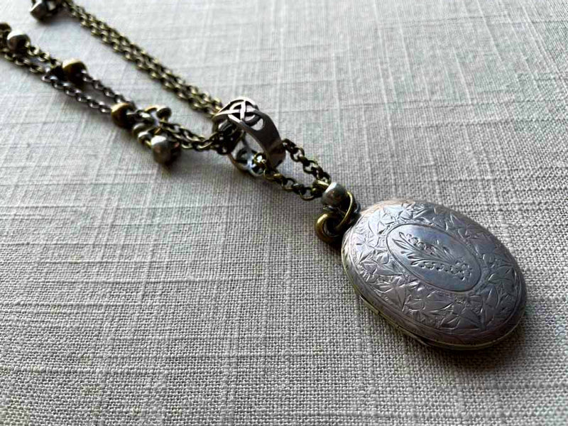 closeup of antique sterling silver locket pendant on chain mix