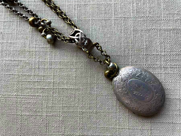 closeup of antique sterling silver locket pendant on chain mix