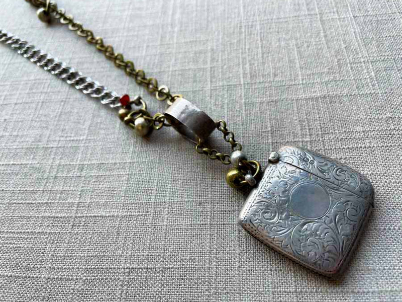 closeup of antique sterling silver match safe pendant on chain mix