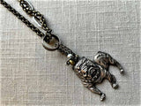 closeup of antique sterling silver bulldog pendant on chain mix