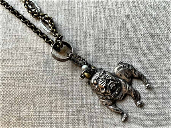 closeup of antique sterling silver bulldog pendant on chain mix