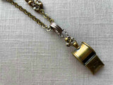 closeup of antique bronze whistle pendant on chain mix