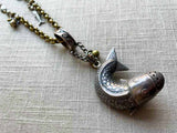 closeup of antique sterling silver fish salt shaker pendant on chain mix