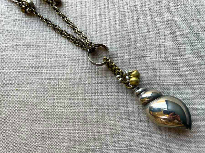 closeup of antique sterling silver seashell pendant on chain mix