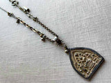 closeup of antique embossed buddha pendant on chain mix