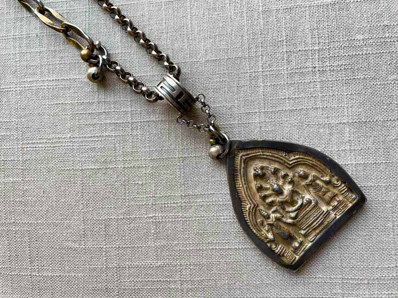 closeup of antique embossed buddha pendant on chain mix