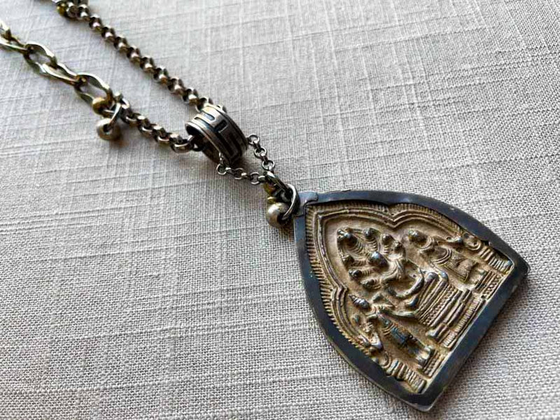 closeup of antique embossed buddha pendant on chain mix