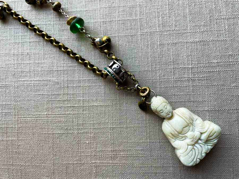 closeup of antique carved buddha pendant on chain mix