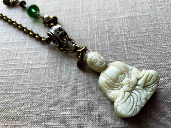 closeup of antique carved buddha pendant on chain mix