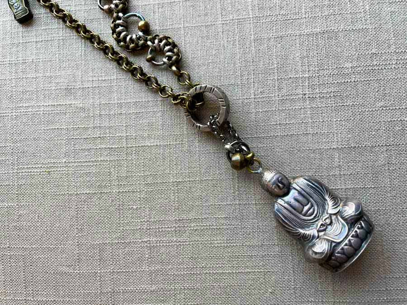 closeup of antique sterling silver buddha salt shaker pendant on chain mix