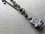 closeup of antique sterling silver buddha salt shaker pendant on chain mix