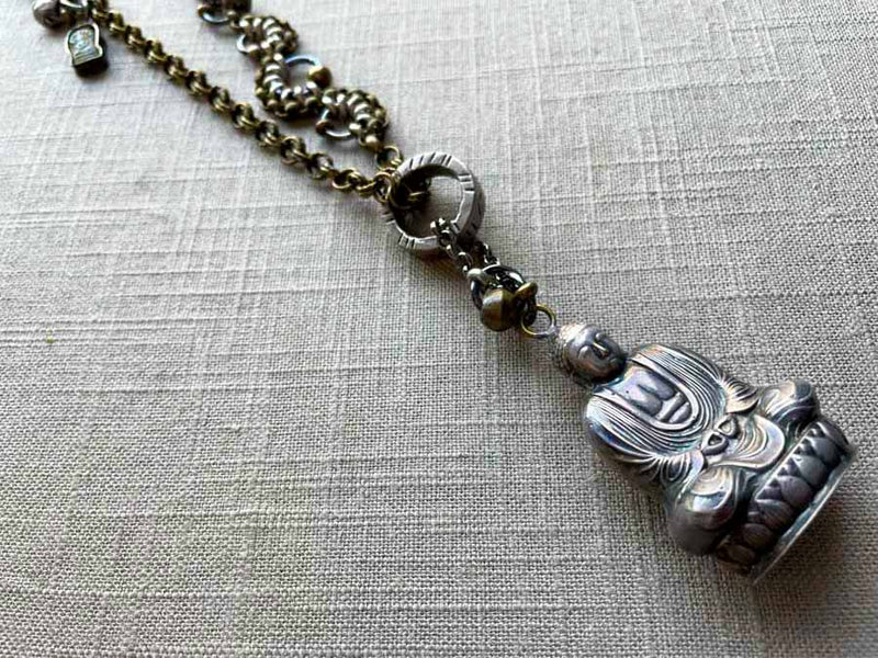 closeup of antique sterling silver buddha salt shaker pendant on chain mix