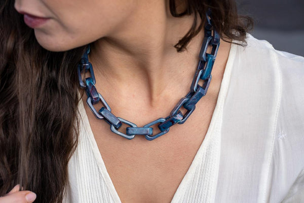 Model wearing resin necklace in blue