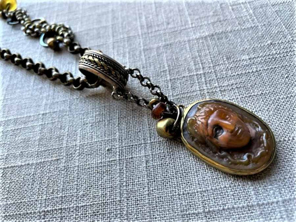 closeup  of antique carved Medusa cameo pendant on chain mix