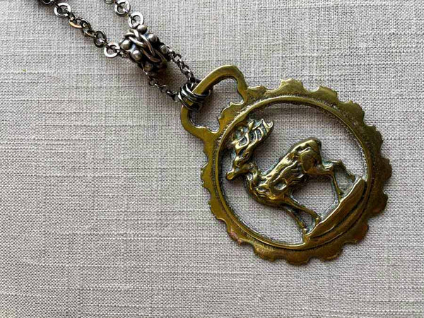 closeup of antique bronze stag ornament pendant on chain mix