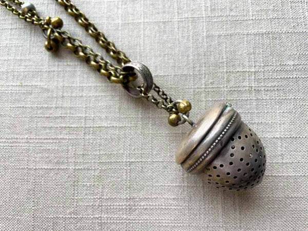 closeup of acorn tea caddy pendant on chain mix