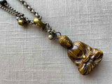 closeup of antique carved jade buddha pendant on chain mix