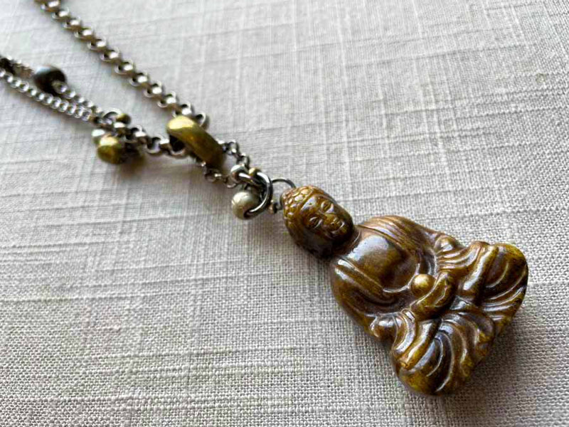 closeup of antique carved jade buddha pendant on chain mix