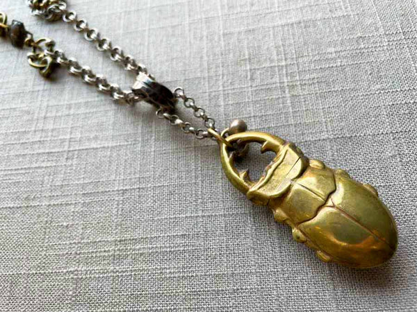 closeup of antique bronze scarab match safe pendant on chain mix