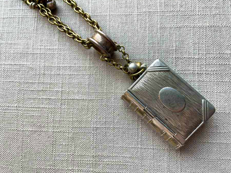 closeup of antique book match safe pendant on chain mix